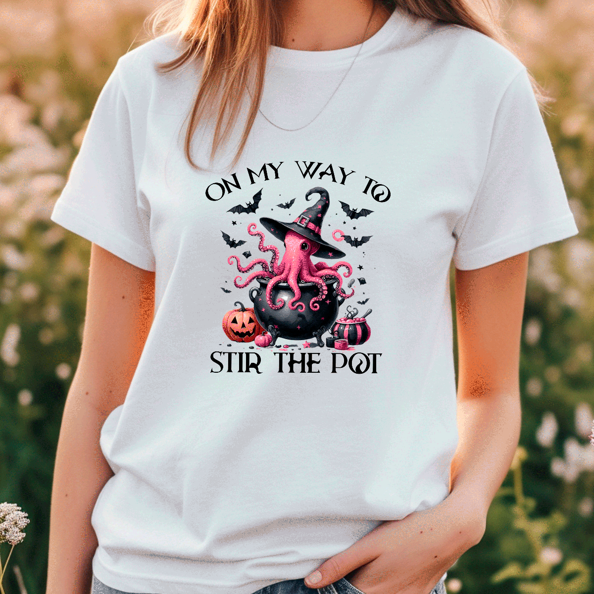 Person wearing a white t-shirt with a Halloween-themed design featuring an octopus in a witch hat and text.