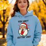 Person wearing a light blue hoodie with a graphic of Santa Claus and text, standing outdoors with trees in the background.