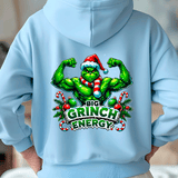 Light blue hoodie with a Christmas-themed graphic of a green character flexing muscles, wearing a Santa hat and scarf, with 'Big Grinch Energy' text.