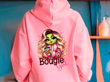 Pink hoodie with a graphic design of a character and the text 'Bougie Girl' against a blue wall.
