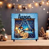 Decorative plaque with a child reading by a window, surrounded by festive decorations.