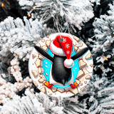 Decorative penguin ornament with a Santa hat on a snowy tree branch