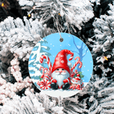 Christmas ornament with a gnome and candy cane design on a snowy background, hanging from a tree.