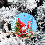 Decorative Christmas ornament with a gnome holding a candy cane and gift, hanging on a snow-covered tree.