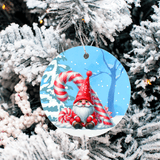 Christmas ornament with a gnome and candy cane design on a snowy background, hanging from a tree.