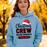 Person wearing a light blue hoodie with 'Christmas Crew Making Memories Together' text and Santa hat graphic, standing in an autumn setting.