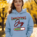 Person wearing a light blue hoodie with 'Christmas Joy Loading' text in an autumn setting