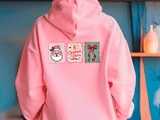 Pink hoodie with Christmas-themed designs on a blue wall background