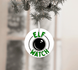 Ornament with 'Elf Watch' design hanging on a Christmas tree.