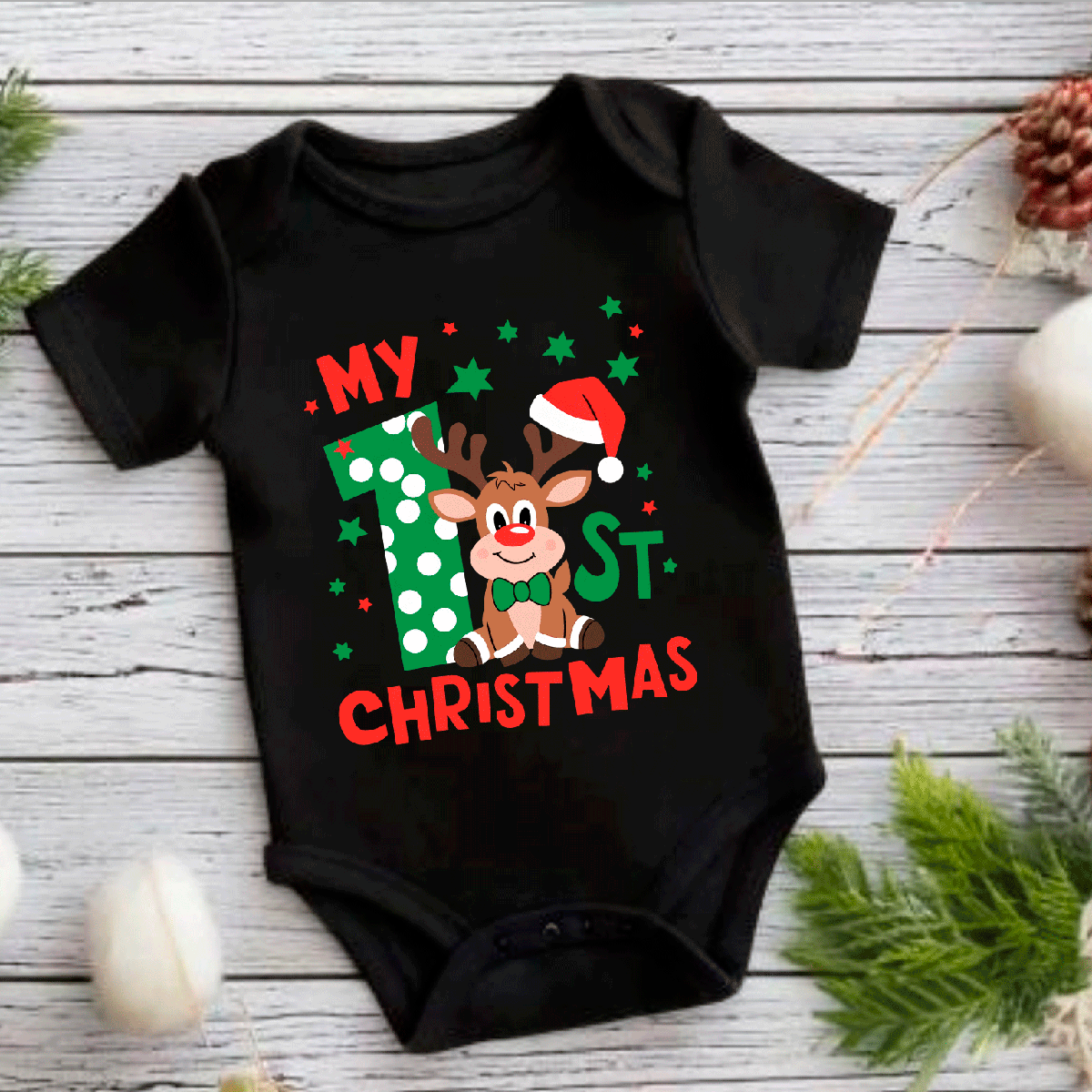 Black baby onesie with Christmas-themed design featuring a reindeer and text on a wooden surface.