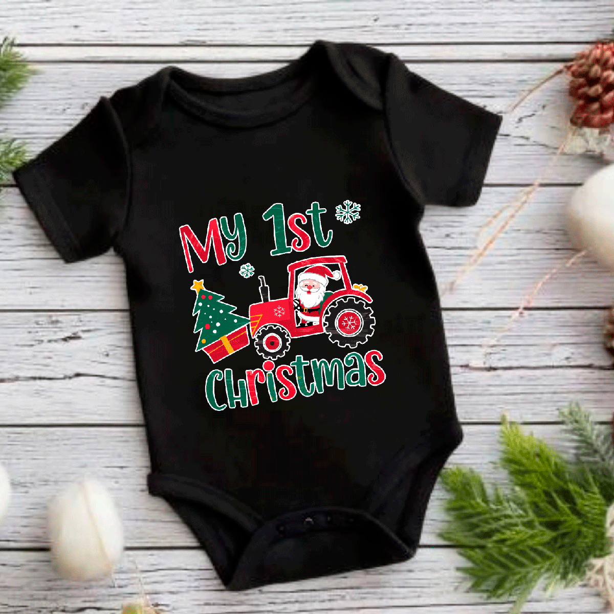 Black baby onesie with Christmas-themed design on a wooden surface.