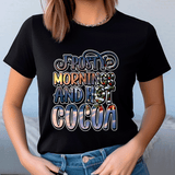 Person wearing a black t-shirt with 'Frosty mornings and hot cocoa' text design.