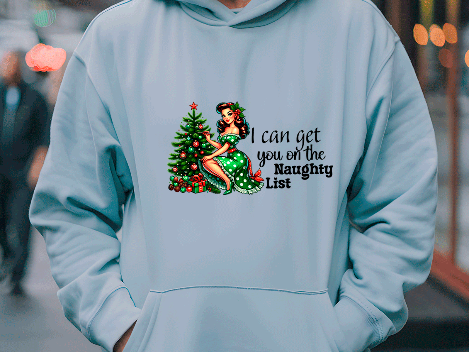 Light blue hoodie with Christmas-themed design and text on a blurred street background