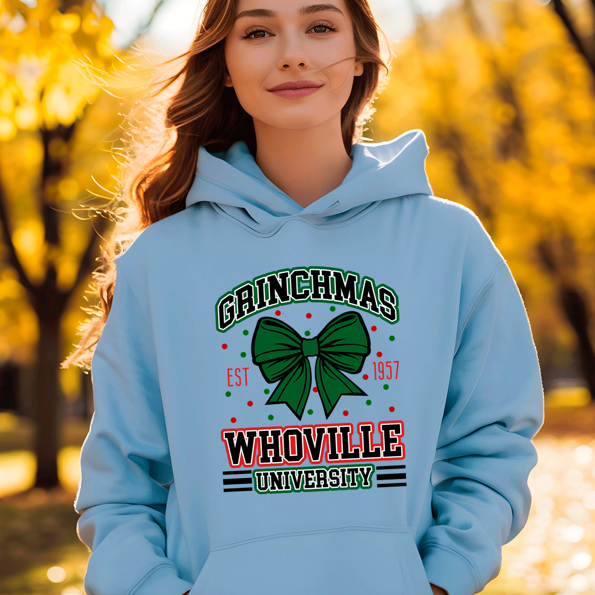Person wearing a light blue hoodie with 'Grinchmas Whoville University' design in an autumn setting.