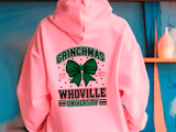 Pink hoodie with 'Grinchmas Whoville University' text and green bow design on a blue background.