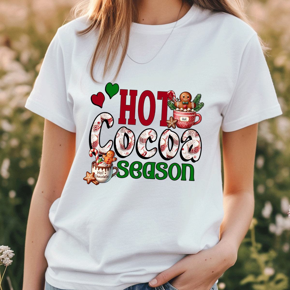 Person wearing a white t-shirt with 'Hot Cocoa Season' graphic design outdoors.
