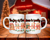 Two white mugs with gingerbread family design and Christmas text on a wooden table.