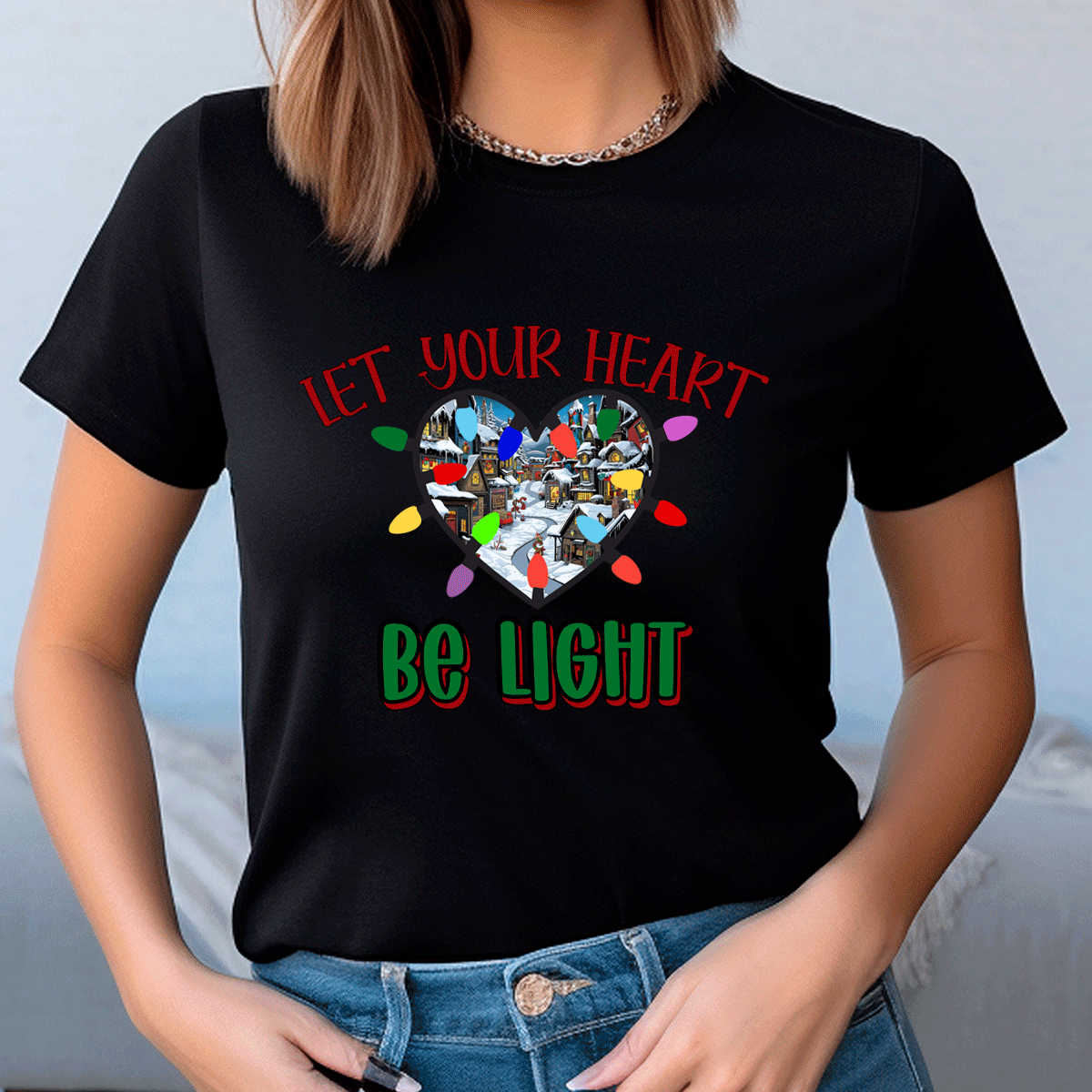 Person wearing a black t-shirt with a heart-shaped design and text 'Let your heart be light' on a plain background