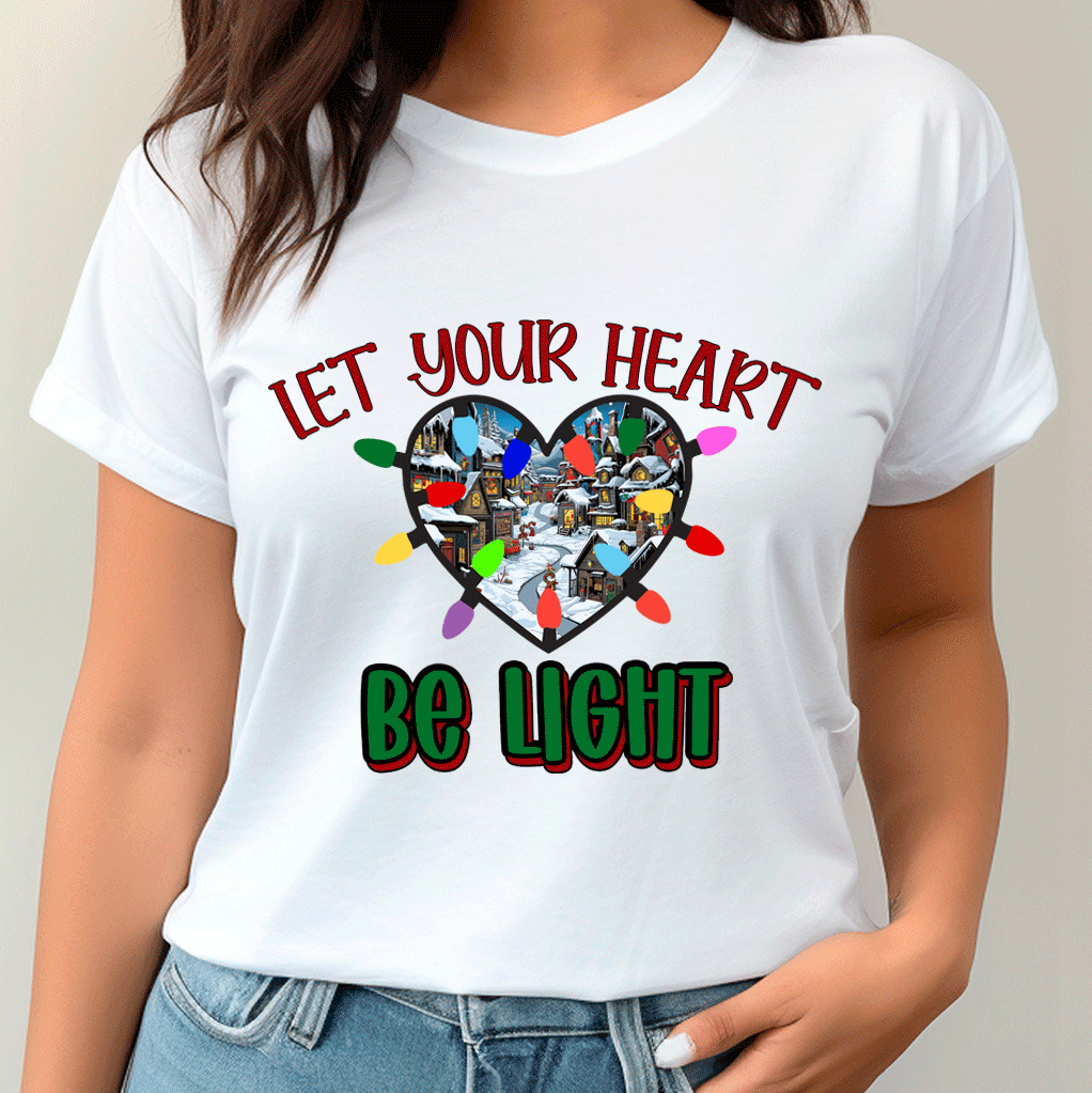 White t-shirt with Christmas-themed design and text 'Let your heart be light' worn by a person.