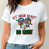 White t-shirt with Christmas-themed design and text 'Let your heart be light' worn by a person.