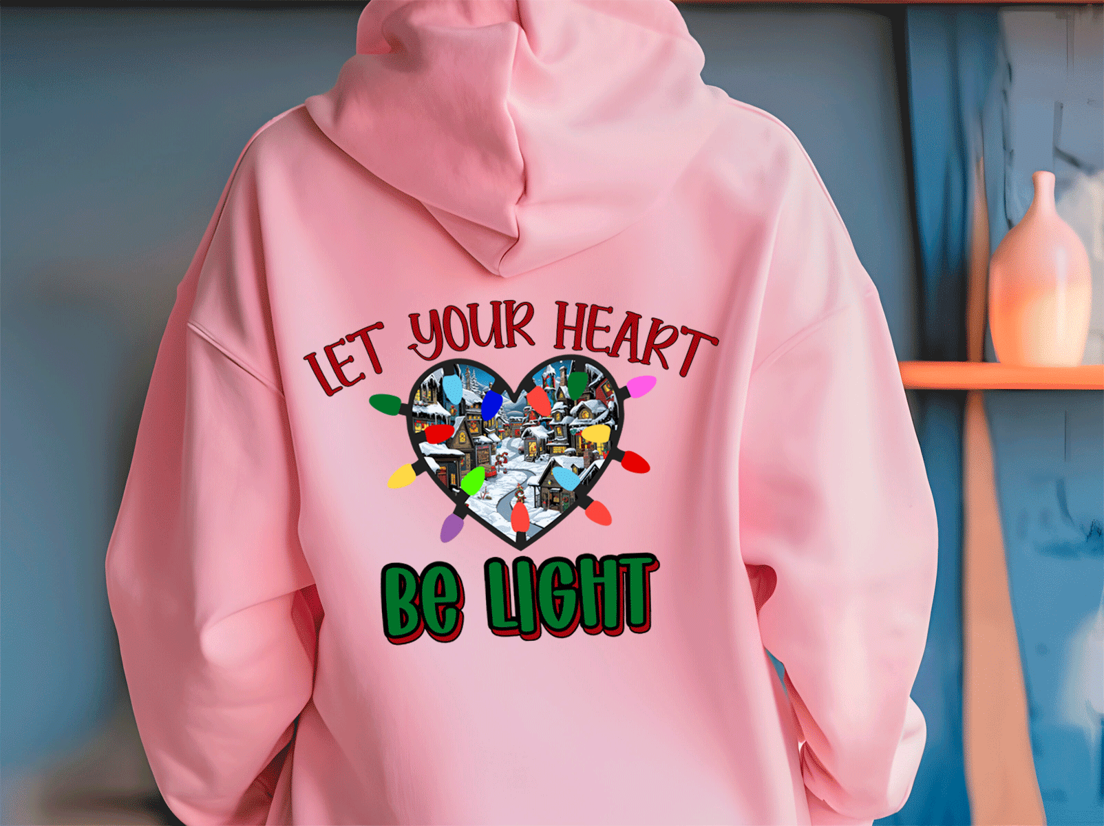 Pink hoodie with a heart design and text on the back against a blue wall.