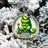 Christmas ornament with a green cat character and 'Master of Mischief' text, hanging on a decorated tree.