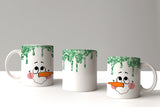 Three mugs with snowman faces and green drips on a white background
