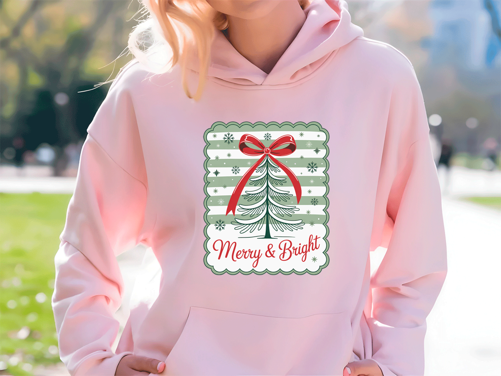 Person wearing a pink hoodie with a Christmas-themed design outdoors.