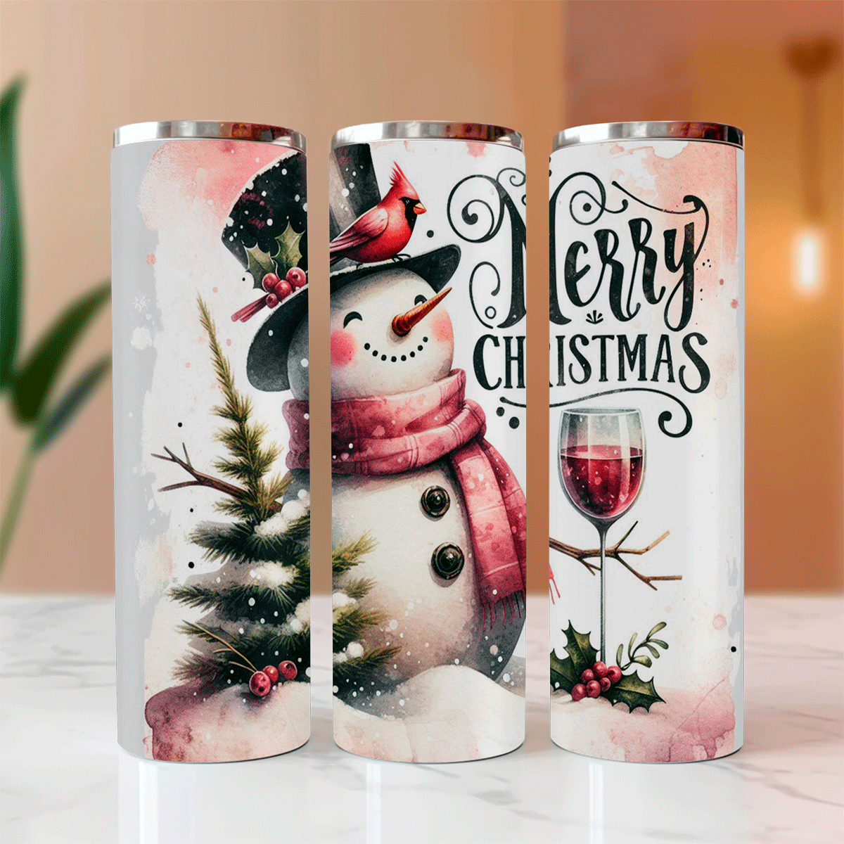 Three Christmas-themed tumblers with snowman, cardinal, and wine designs on a blurred background.