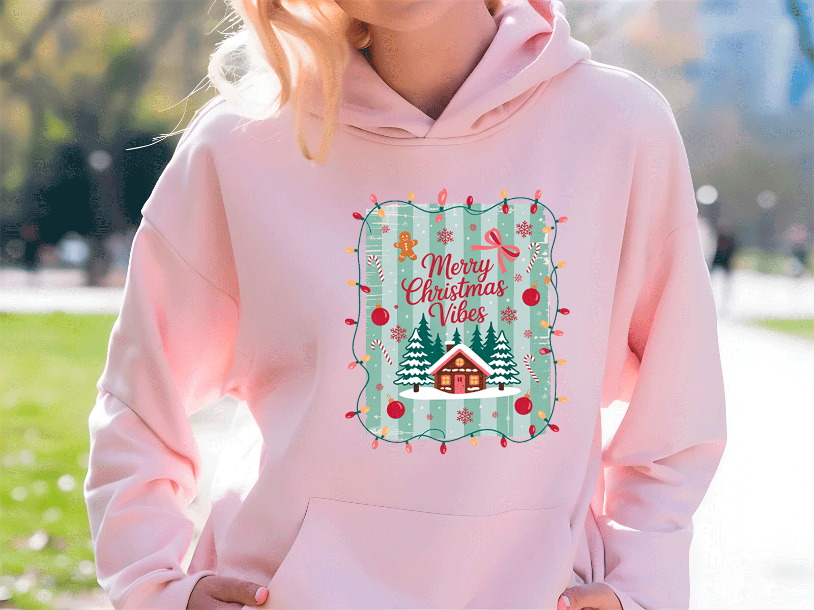 Person wearing a pink hoodie with a Christmas-themed design outdoors.