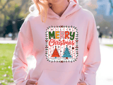 Person wearing a pink hoodie with a 'Merry Christmas' design outdoors.