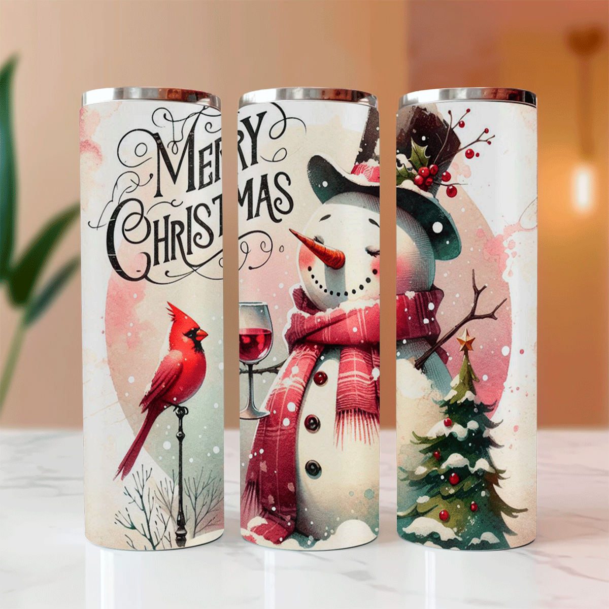 Three Christmas-themed tumblers with snowman, cardinal, and wine glass designs on a blurred background.