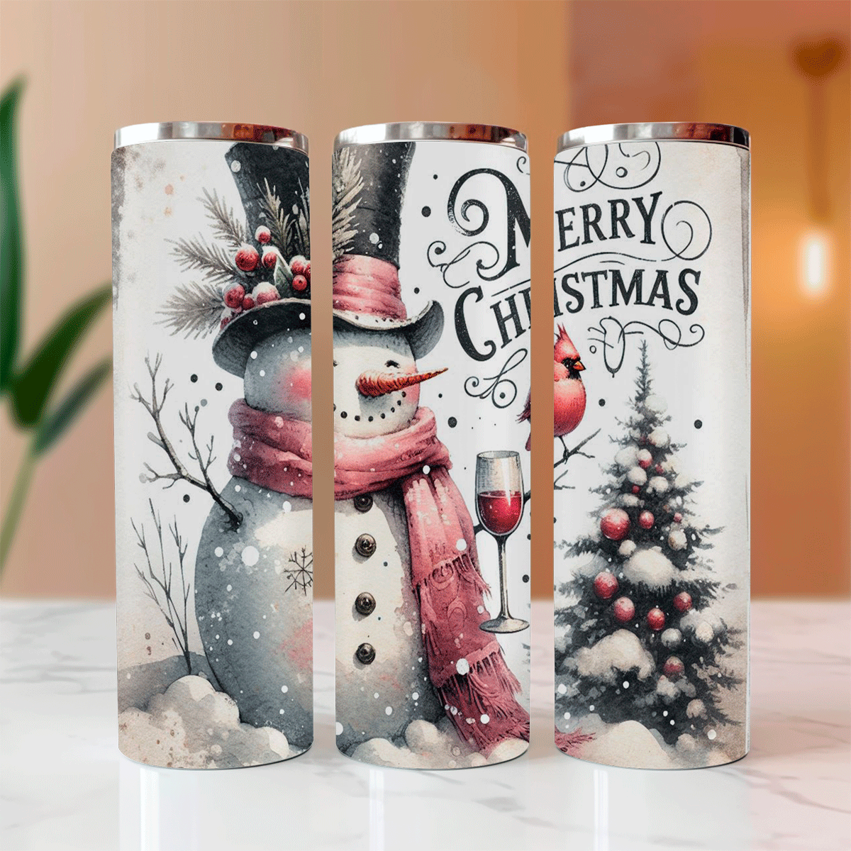 Three Christmas-themed tumblers with snowman, wine glass, and tree designs on a white surface.