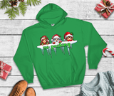 Green hoodie with Christmas-themed design on a wooden surface with festive decorations.