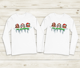 Two white long-sleeve shirts with Christmas-themed design on a wooden surface