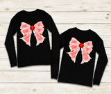Two black long-sleeve shirts with pink bows on a wooden surface