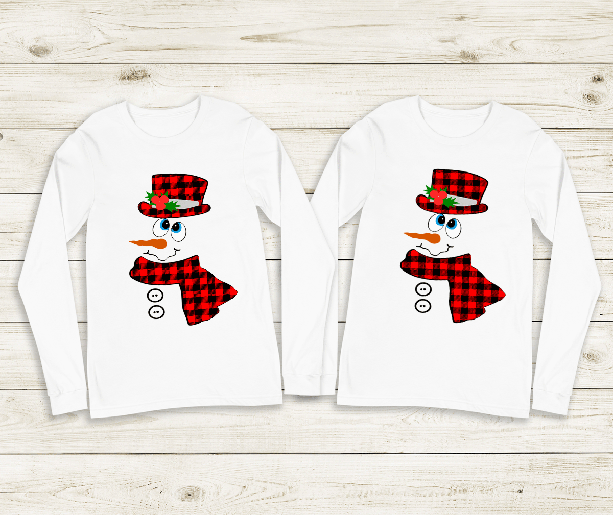 Two white long-sleeve shirts with snowman designs on a wooden surface