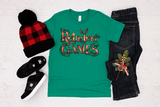 Green t-shirt with 'Reindeer Games' design, black jeans, red and black checkered hat, and black shoes on a light gray background.