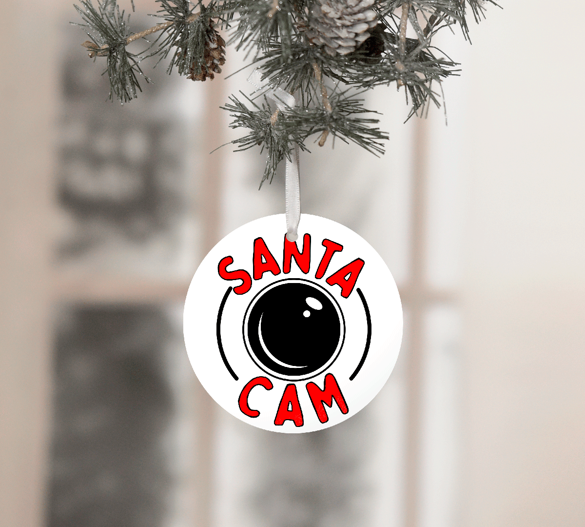 Round ornament with 'Santa Cam' text hanging on a Christmas tree.