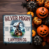 Halloween-themed product with pumpkins and a sign for Silver Moon Lantern Co. on a slate surface.