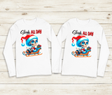 Two long-sleeve shirts with a graphic of a skeleton in a Santa hat and sleigh, with 'Sleigh All Day' text, on a wooden surface.