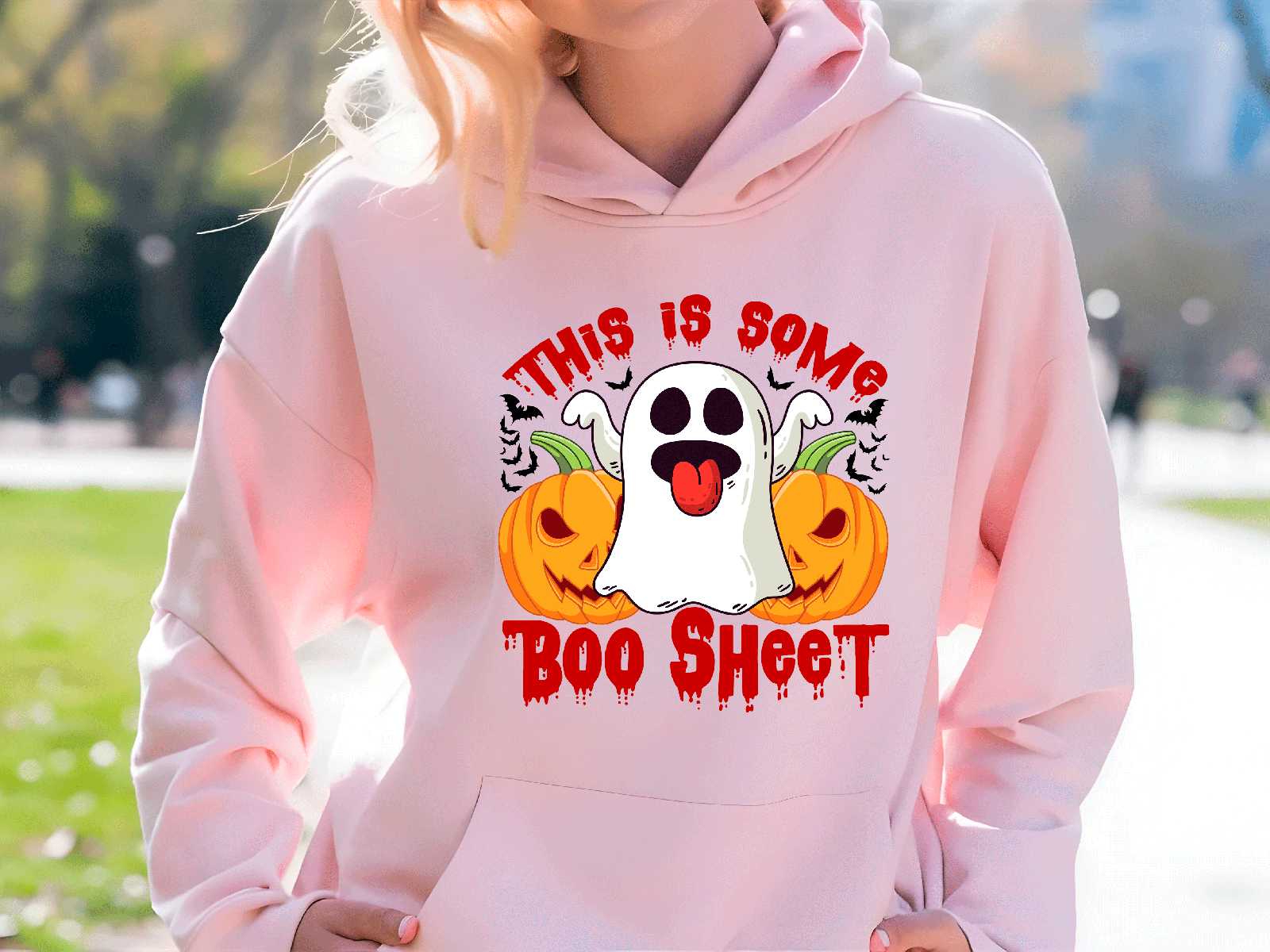 Person wearing a pink hoodie with Halloween-themed design outdoors