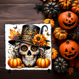 Decorative skull with a top hat surrounded by pumpkins on a wooden background