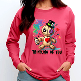 Person wearing a pink sweatshirt with a cartoon skeleton holding a heart and text 'Thinking of You'.