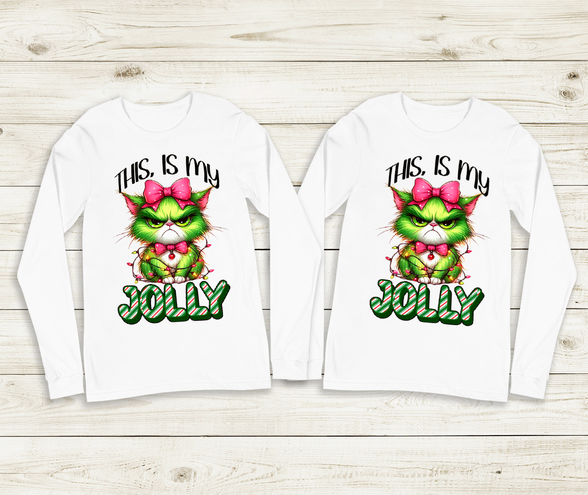 Two white long-sleeve shirts with a festive design featuring a green character with a pink bow and text on a wooden background.