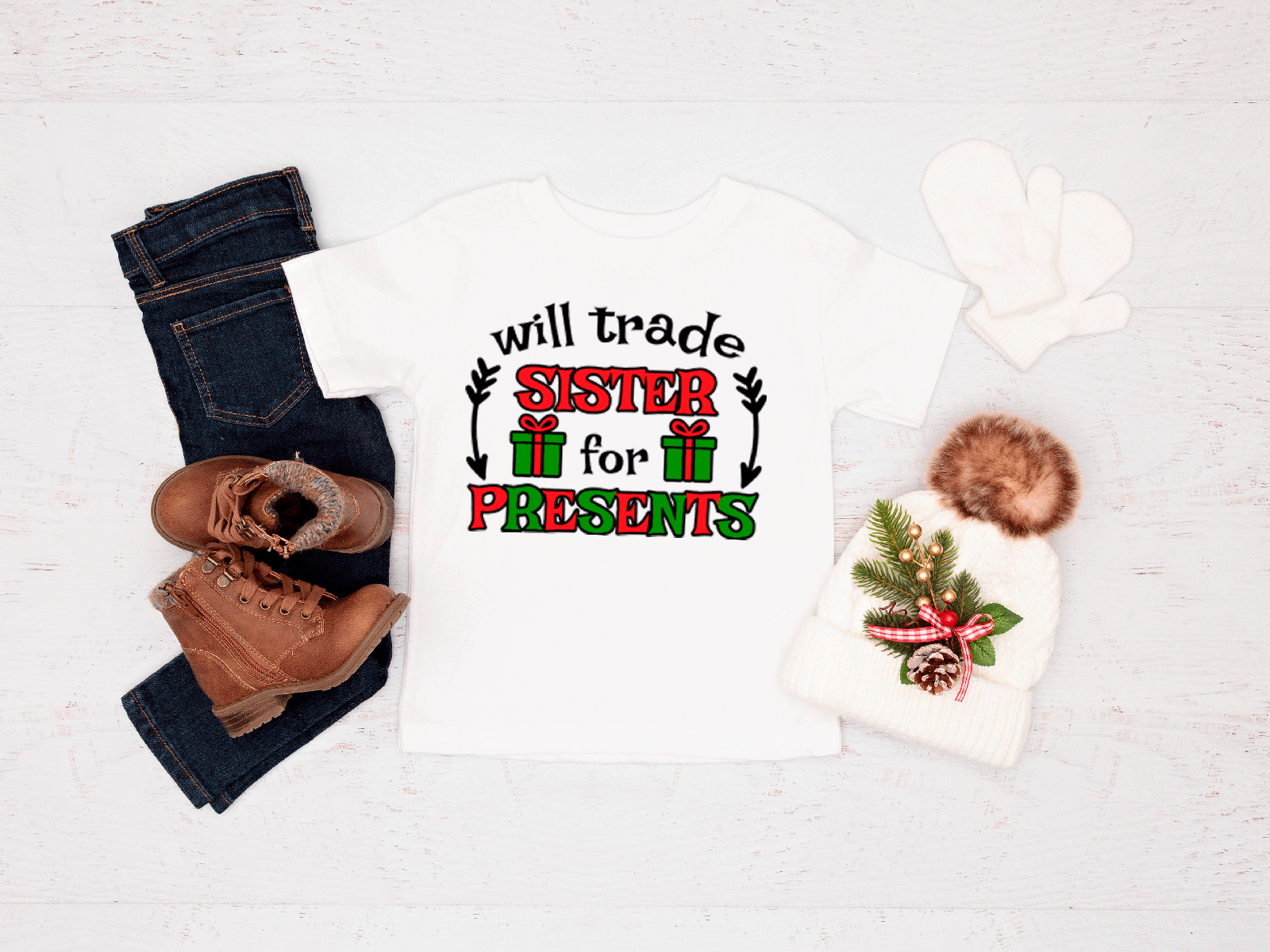 White tee with Christmas-themed text and graphics, paired with jeans and boots on a light background.