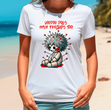 Person wearing a white t-shirt with a cartoon voodoo doll design on a beach.