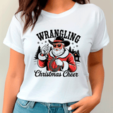 White t-shirt with a graphic of a Santa Claus holding a rope and text 'Wrangling Christmas Cheer' worn by a person.